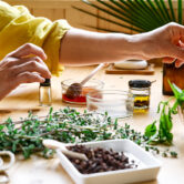 Woman prepares aromatherapy session at the table with essential oil diffuser medical herbs, different types of oils and essences. Aromatherapy and alternative medicine concept. Natural remedies.